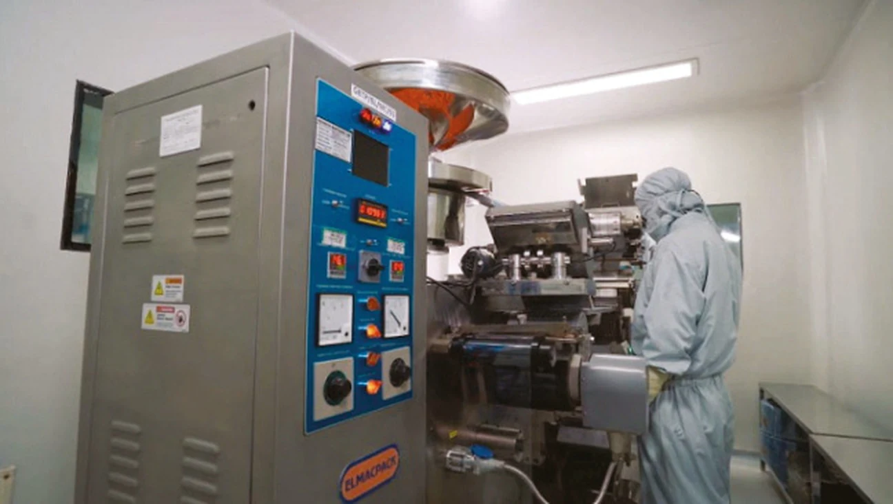 Technician monitoring a high-speed tablet compression machine on the production floor